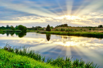 Summer landscape of sunrise by the river with reflections