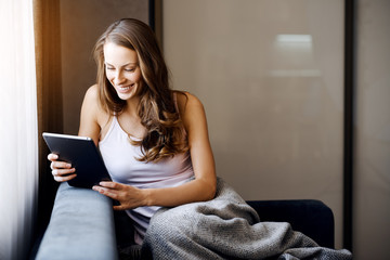 Young woman at home reading a book on your tablet