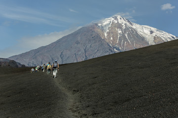 Tourist pass cooled lava flow from a new crater on the slope of a volcano Tolbachic and a group of tourists, which boosts his - Kamchatka, Russia © vadim_petrakov
