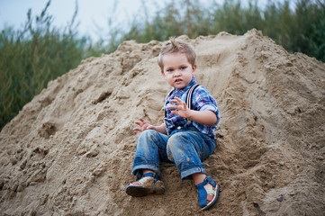 Little cute boy riding a roller coaster of sand on the bottom. Memories of childhood and carefree