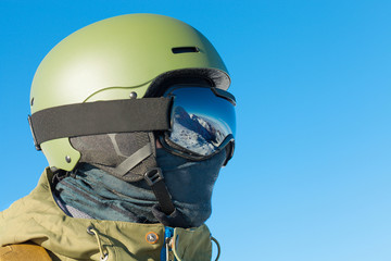 Close up shot of snowboarder in goggles with reflection of snowed mountains in it