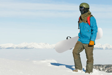 Fototapeta na wymiar Snowboarder holding snowboard in hand and enjoying the landscape at the top of the mountain
