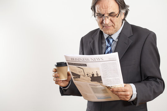 Businessman reading newspaper on gray background
