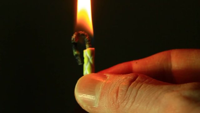 Close up of male hand, holding small birthday candle.