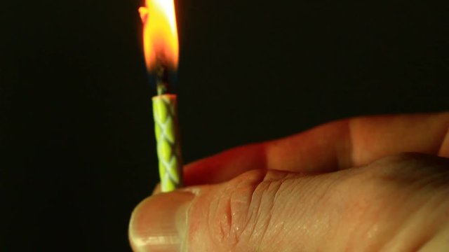 Close up of male hand, holding small birthday candle.