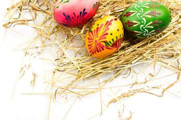 Fototapeta na wymiar Top View Colorful Easter Eggs with Wax Ornaments on Golden Dry Hay