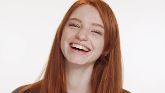 Close footage of young Caucasian red haired teenage girl smiling laughing on white background