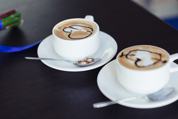 two cups of coffee on the table with wedding rings