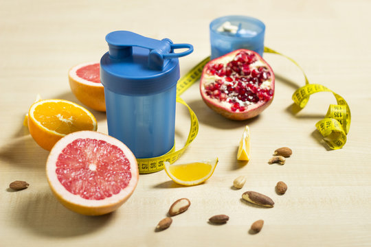 Fitness and healthy life concept. Fruits and nuts on a wooden table. Fitness equipment. Shaker and supplement measuring tape on a table.