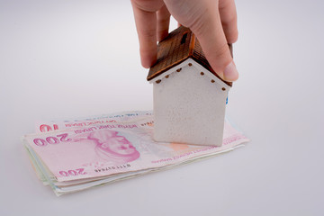 Hand holding  a model house by the side of Turkish Lira banknote