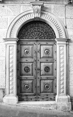The entrance wooden door in an old Italian house (black and white).