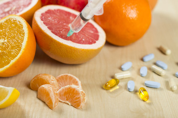 Needle and syringe injected in the fruit. Nutrition concept. Enhanced fruits. GMO. Healthy life versus unhealthy life. Fruits and pills on the table.