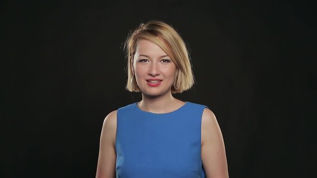 Mitis young woman in a blue dress posing on a black background. Positive emotions.
