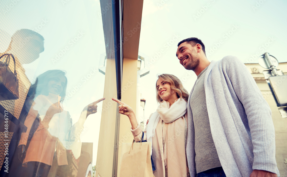 Wall mural happy couple with shopping bags at shop window