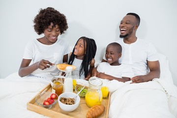 Obraz na płótnie Canvas Smiling parents and kids having breakfast in bedroom