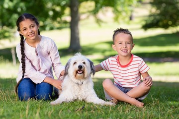 Siblings sitting with their pet dog in park