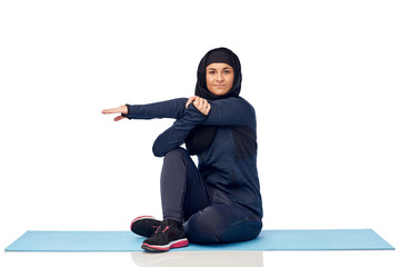 muslim woman doing sportand stretching on mat