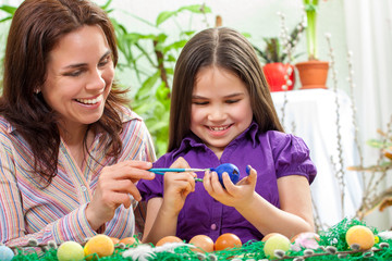 Mother and her children paint easter eggs