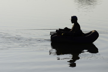 pescatore su natante mentre pesca in lago