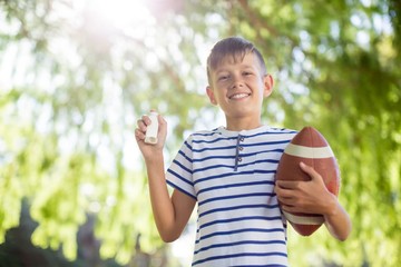 Boy holding asthma inhaler and a rugby ball - obrazy, fototapety, plakaty