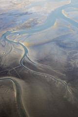 aerial view of the mudflat coastline at low tide with water winding in the mud and sand bank, Frisian island Ameland, The Netherlands