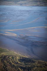 aerial view of the mudflat coastline at low tide with water winding in the mud and sand bank, Frisian island Ameland, The Netherlands