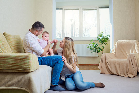 Cute baby playing with parents in the room.