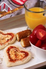 Heart shaped Bread pizza served in a tray with orange juice Mozzarella sticks and cherry tomatoes