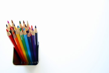 A lot of colored pencils inside a tin can on the white background.