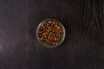 Coffee beans in a glass bowl - top view. On  black background.