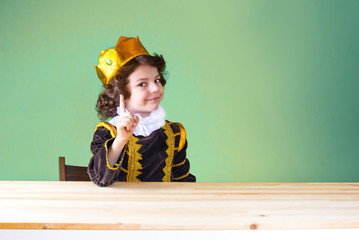 Young handsome prince threatens forefinger looking at the camera. Close-up. Green background.