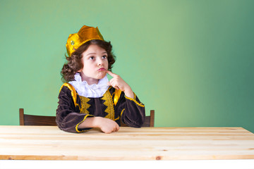 Little curly king sternly looking up. Purple Suit. Green background.