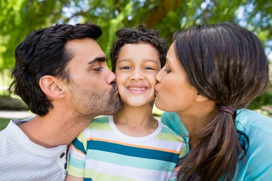 Boy being kissed by his parents in park