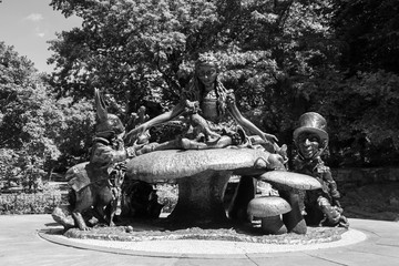 Alice in Wonderland surrounded by the Mad Hatter, the White Rabbit and a few of her other friends sculpture at Central Park in black and white style