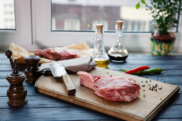 Raw beef steaks with spices on wooden background