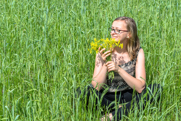 Young woman smelling flowers on summer field