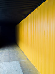 Cargo container deep inside to the dark with yellow wall
