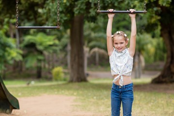 Fototapeta premium Girl hanging on a playing equipment in park