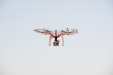 Flying drone with camera on the sky at sunset