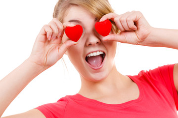 Funny woman holds red hearts over eyes