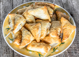 Fresh baked puff pastry triangles on a plate on wooden table