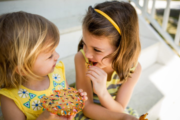 Two young girls sharing a cookie, close up 