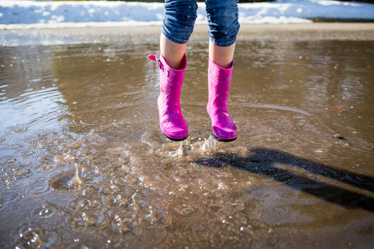 Child in pink wellies, jumping in puddle 