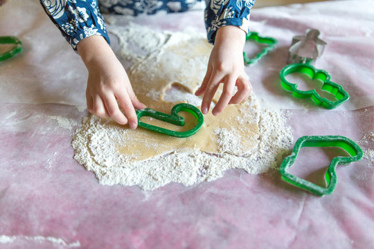 Childs hands making cookies with festive cutters 