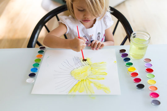 Child painting sun with watercolors