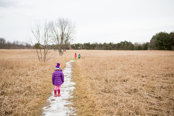 Three children walking on trail in woodland 