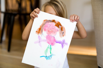 Child holding up figure painting 