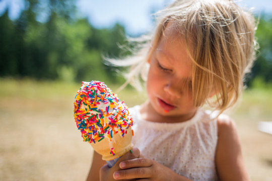 Child holding and looking at ice cream with sprinkles 