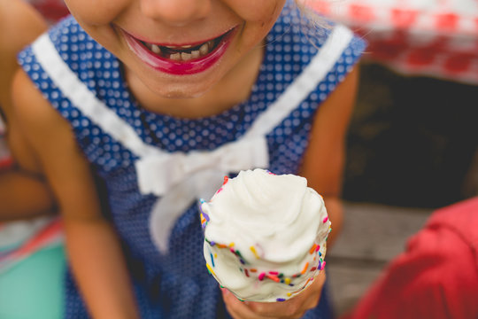 Girl wearing lipstick with missing tooth, holding ice cream 