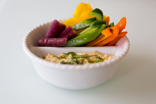 Bowl of hummus and sliced peppers and carrot 